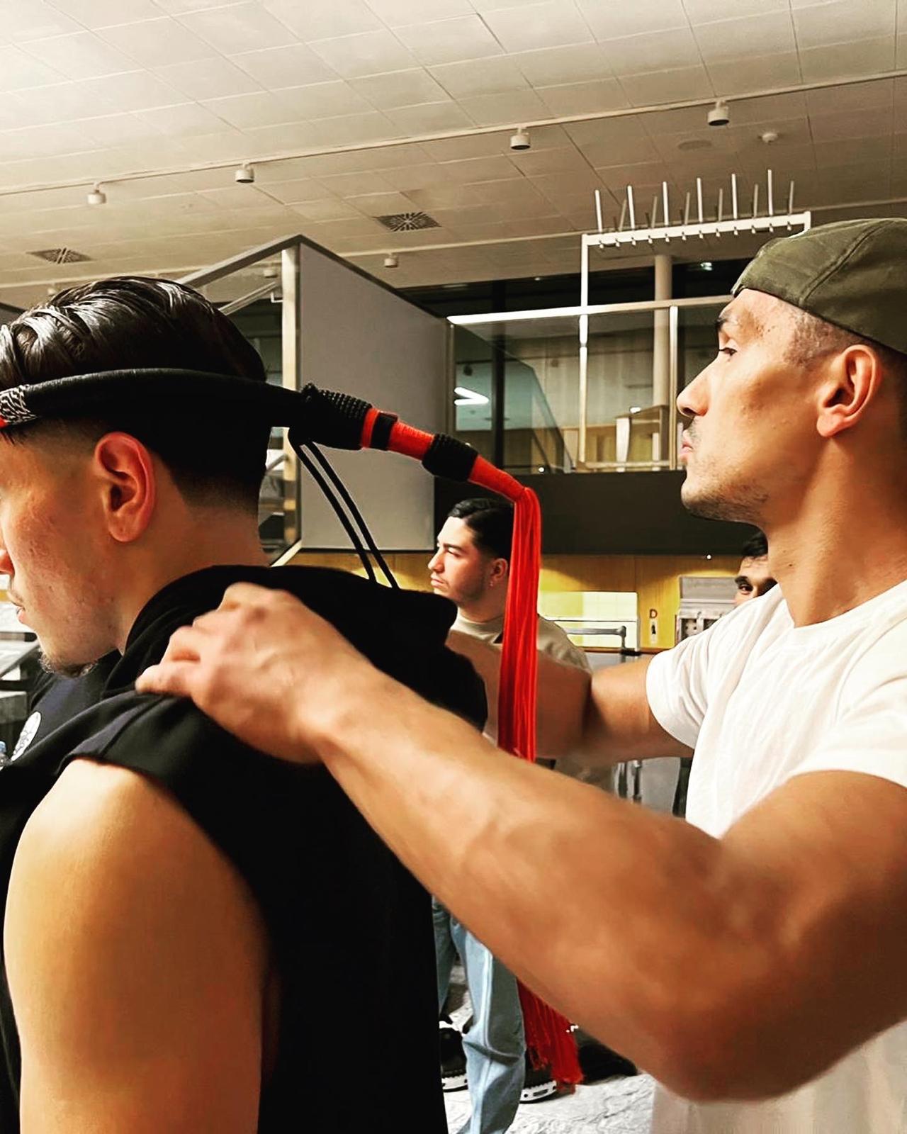 Merlin Fröhner bindet einem Athleten das Mongkhon um
